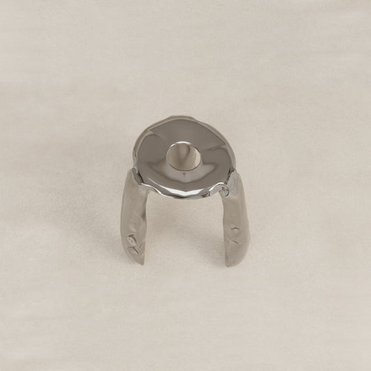 The Araknid Stool Large is a sturdy, shiny metallic stool with three curved legs and a circular top featuring a central hole, displayed on a plain, light-colored surface.
