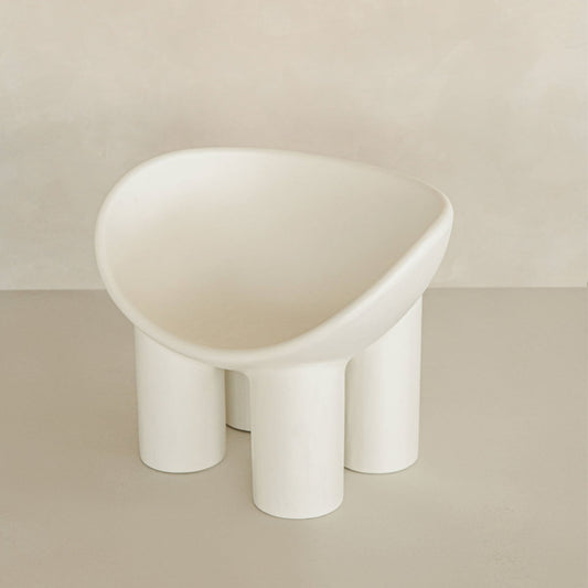 The Arrio Chair features a modern, minimalist design with a rounded seat and four thick cylindrical legs, showcasing avant-garde style against a neutral beige background.