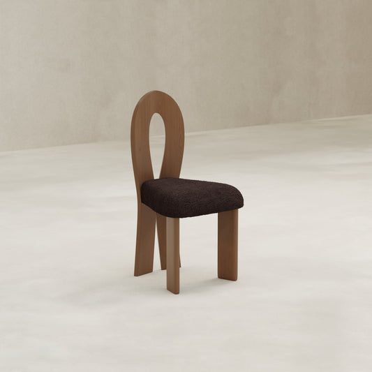 The Nola + 2 Aveline Dining Set features a modern wooden chair with an oval open backrest, three legs, and a dark, textured cushioned seat—ideal for dining spaces with light floors and neutral walls.