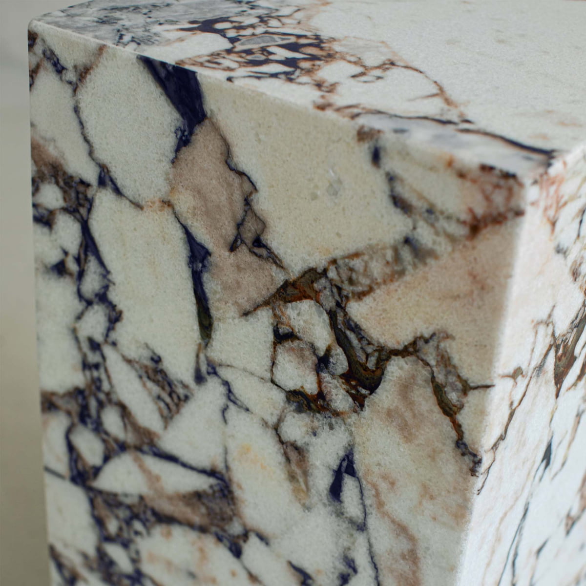 A close-up of the Turkish Calacatta Plinth Tall shows its smooth surface with cream, brown, and dark gray veining patterns for a polished, elegant look.