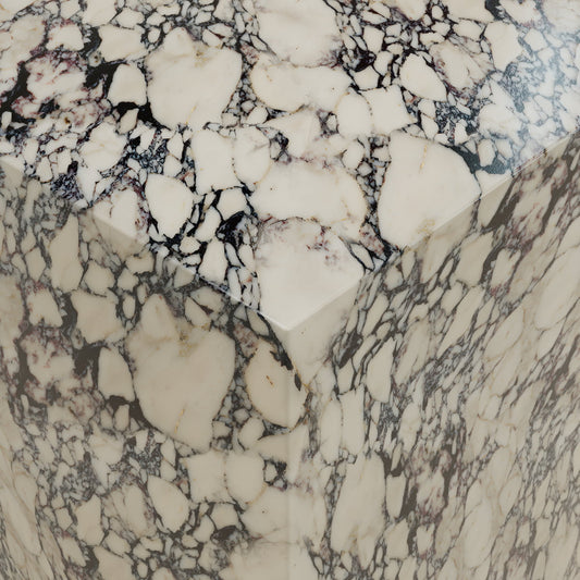 Close-up of the Azurine Tall Tower Plinth, showing its polished marble surface with irregular cream patterns and dark veins, highlighting the stones texture and angular edges for an elegant look.