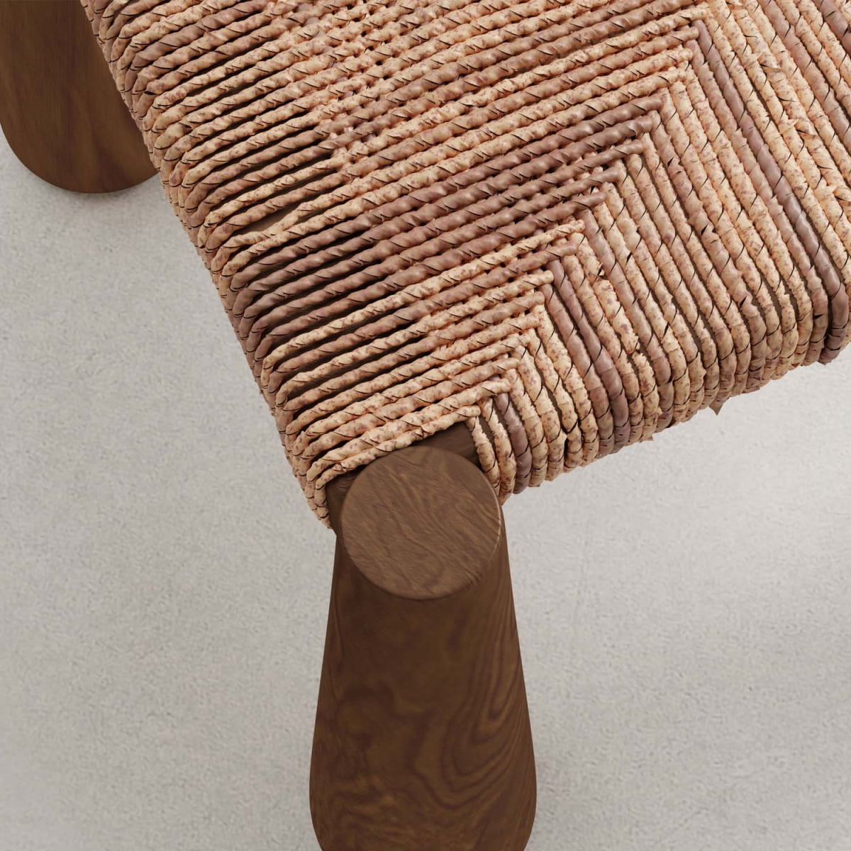 Close-up of the Bardo Chair, a handcrafted piece with a woven natural fiber seat on a wooden frame with rounded legs, set on a light-colored textured surface.