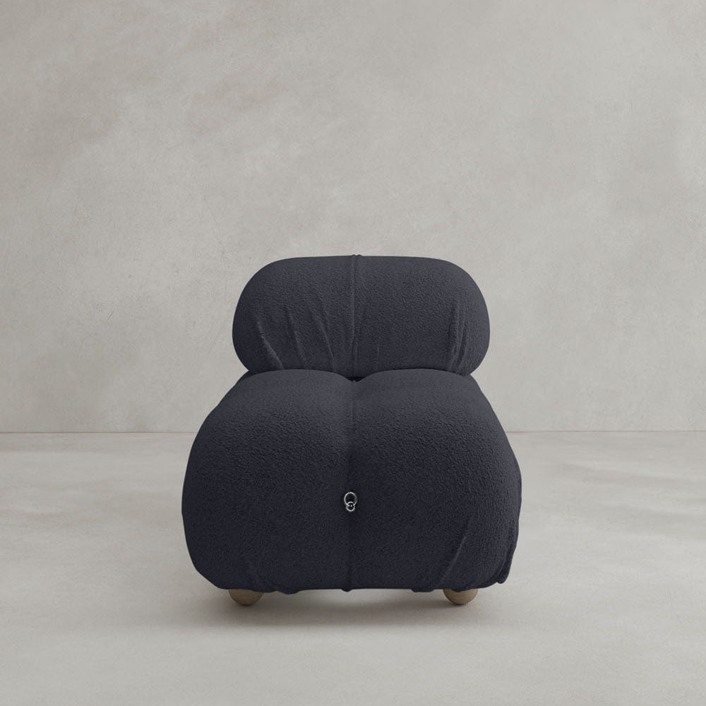 The Belmont Chair 2/3Rd Modular Sectional, a modern black armchair with plush cushions and marshmallow-like curves, sits on a light textured floor against a plain beige wall.
