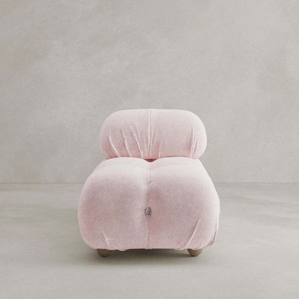The Belmont Chair 2/3Rd Modular Sectional features modern, armless design with soft curves and pale pink upholstery, showcased against a light gray background.