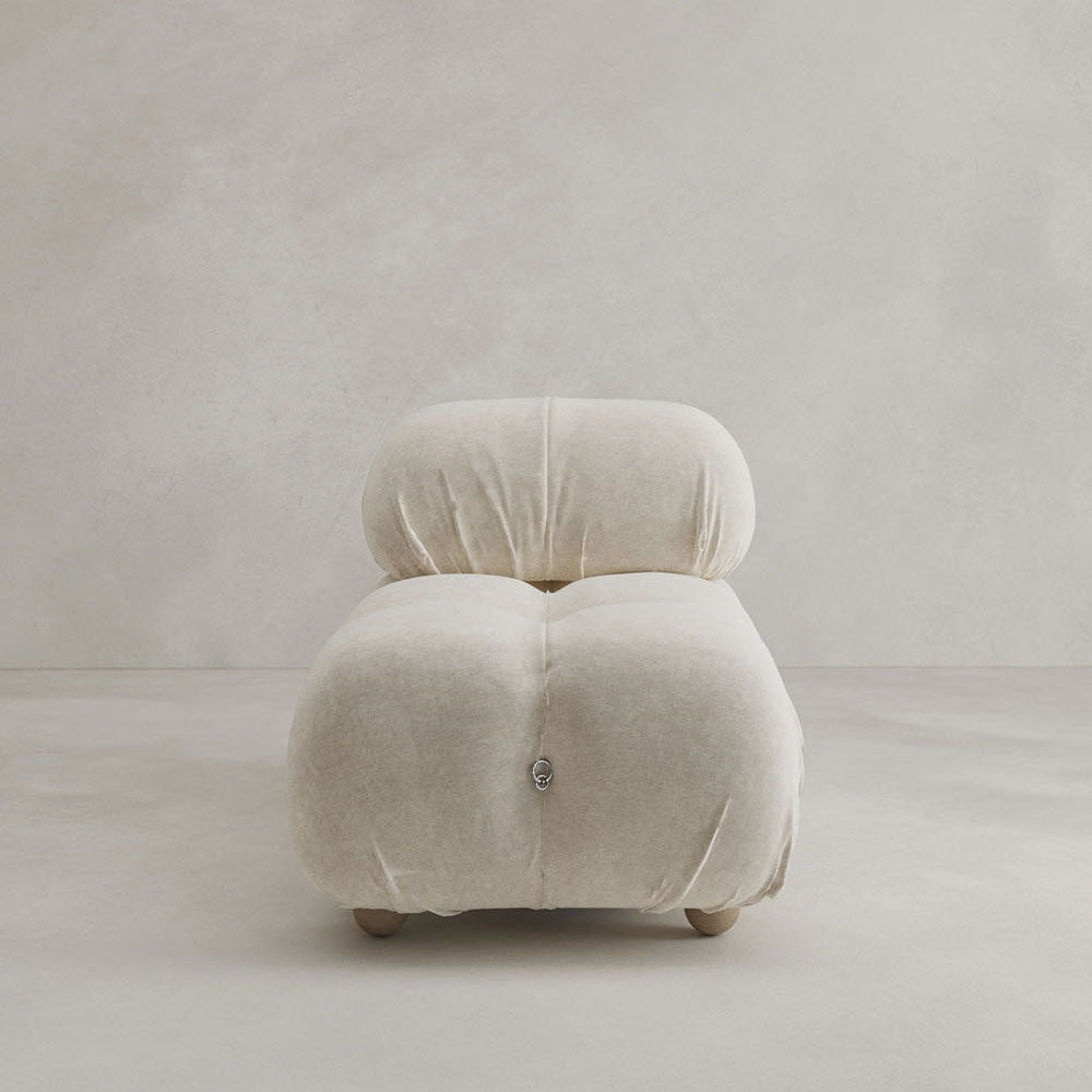 The Belmont Chair 2/3Rd Modular Sectional features a cream color, plush upholstery, rounded tufted cushions, and short legs, creating a marshmallow-like look perfect for minimalist spaces.