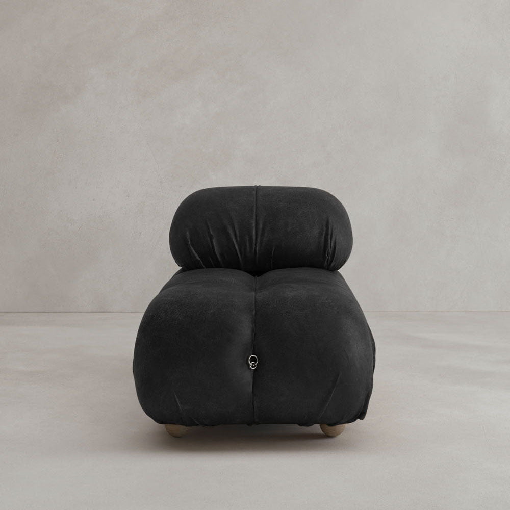 The Belmont Chair 2/3Rd Modular Sectional showcases modern, minimalist black curves with tufted upholstery and short, round wooden legs—a stylish classic on a neutral floor against a plain beige wall.