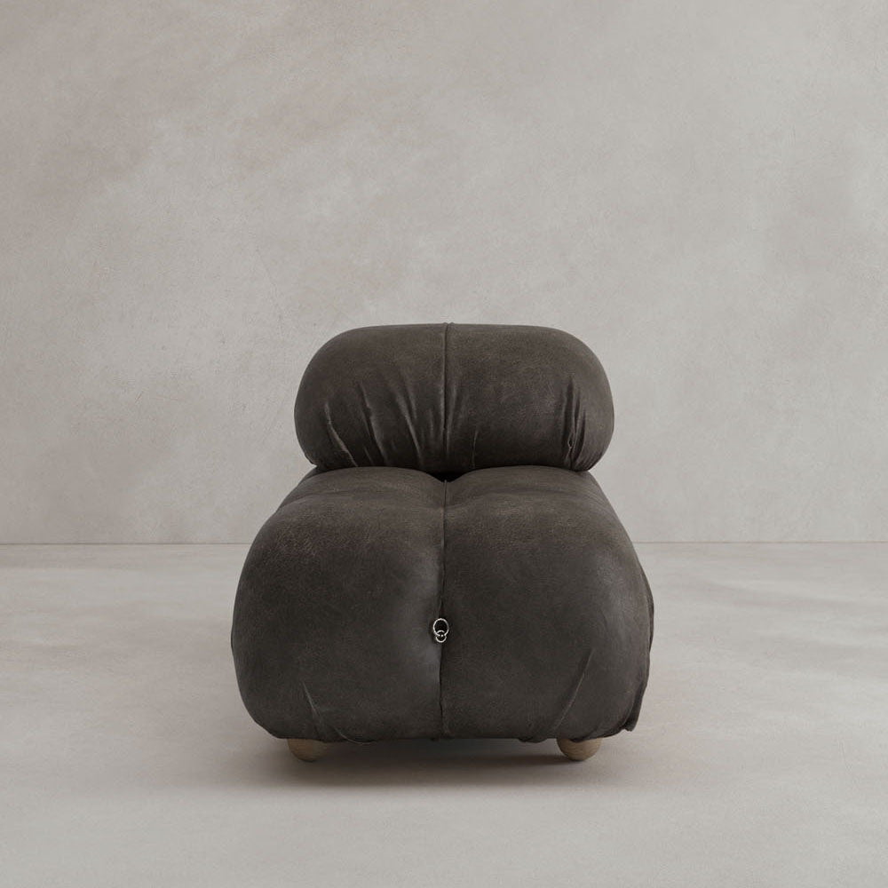 The Belmont Chair 2/3Rd Modular Sectional features a modern, low-profile design with marshmallow-like curves, dark tufted upholstery, soft rounded edges, and no visible armrests, set against a minimalist background.