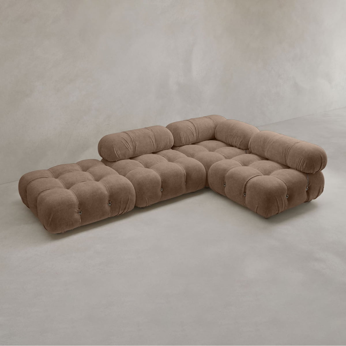 The Belmont Sofa Combination C is a modern, low-profile sectional in soft brown fabric with tufted cushions and marshmallow-like curves, rounded edges, and classic appeal, set against a light gray minimalist background.