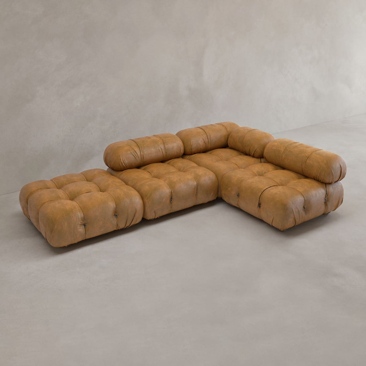 The Belmont Sofa Combination C is a brown, tufted modular sectional with marshmallow-like curves, low seat, and rounded cushions in an L-shape on a light floor against a neutral beige wall.