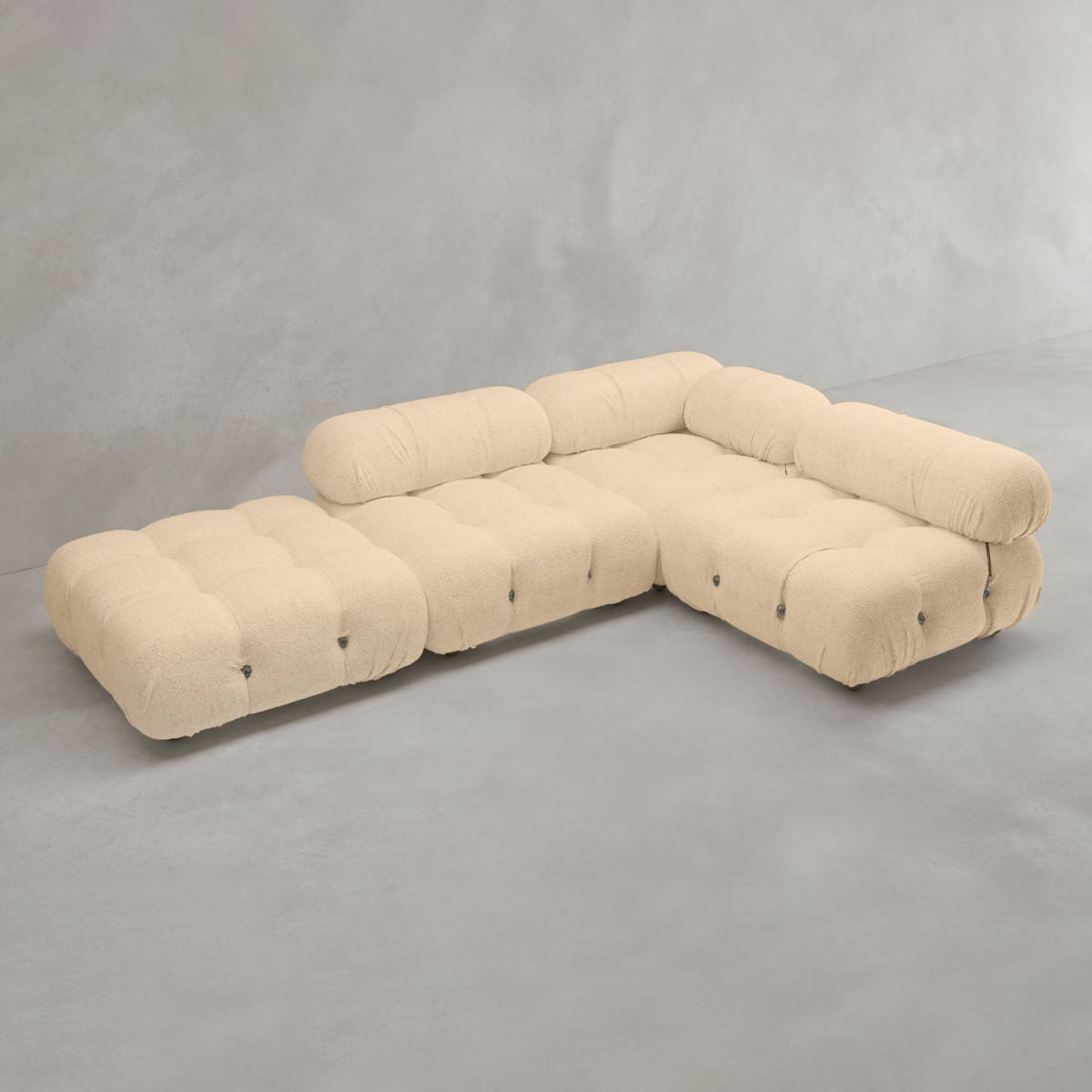 The Belmont Sofa Combination C is a modern, modular sectional with beige tufted fabric and rounded, marshmallow-like cushions, arranged in an L-shape on a plain gray floor against a light gray wall.