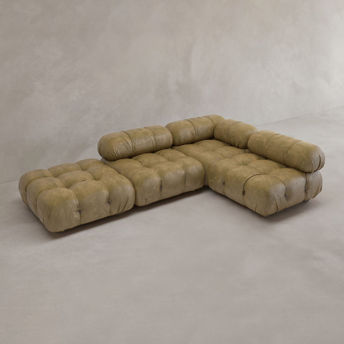 The Belmont Sofa Combination C is a modular, vintage-style sectional with tufted light brown leather cushions, low backrests, and marshmallow-like curves, shown in an empty room with light walls and flooring.