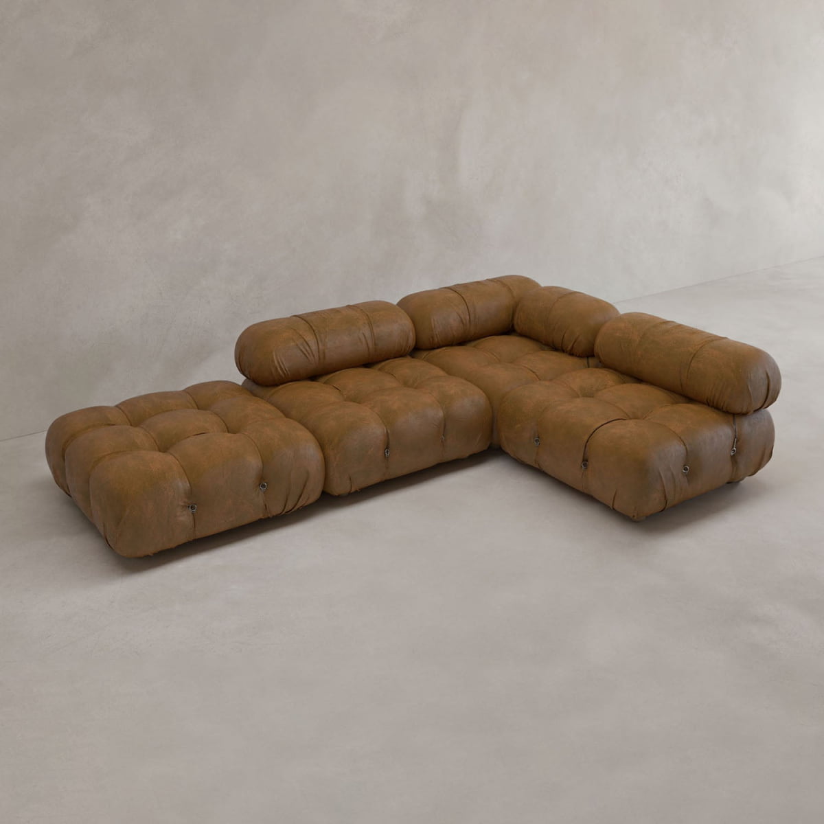 The Belmont Sofa Combination C, a brown tufted modular sectional with marshmallow curves and cylindrical backrests, is arranged in an inviting L-shape on a light floor against a neutral wall.