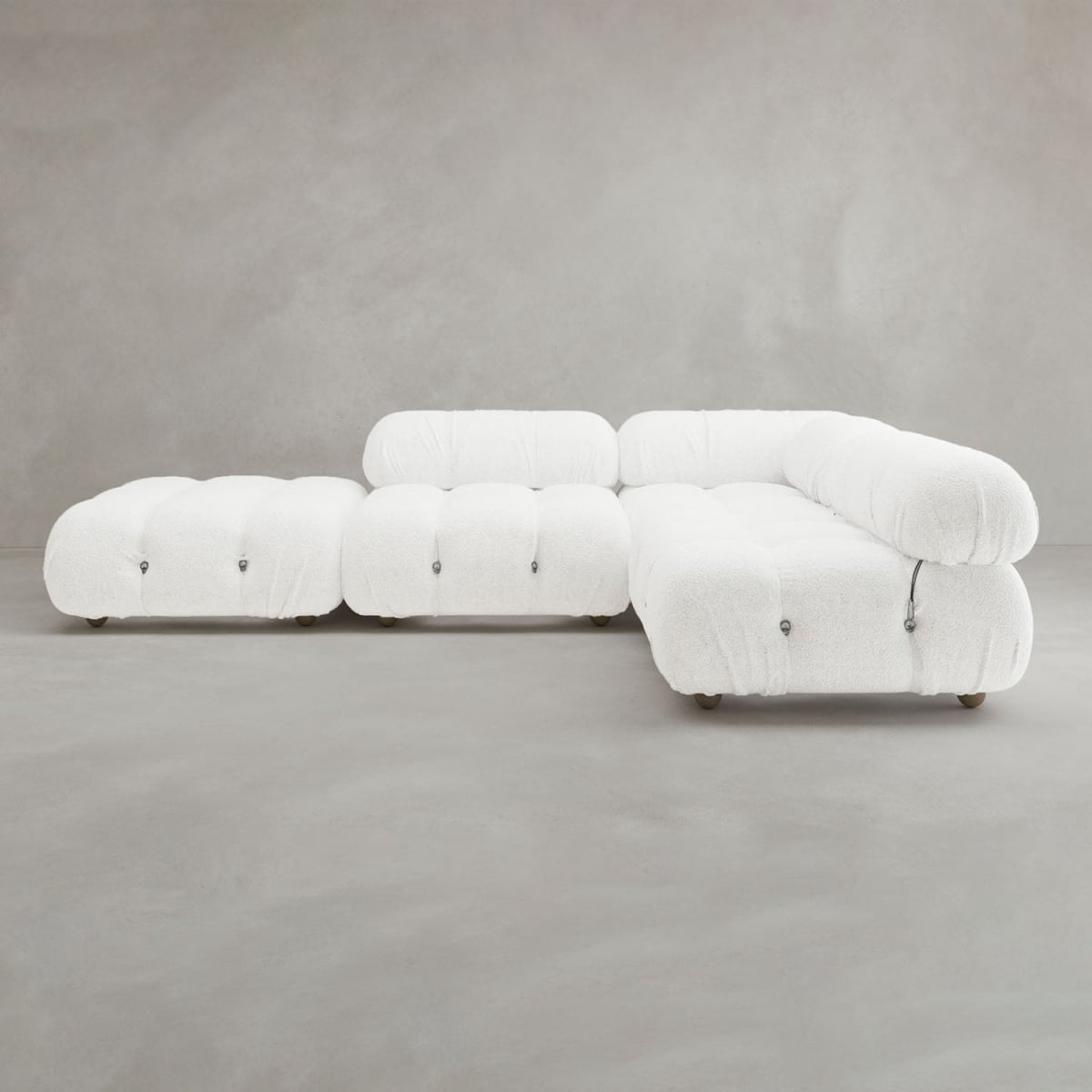 The Belmont Sofa Combination C is a modular white tufted sectional with marshmallow-like curves and rounded edges, highlighting its iconic classic design against a plain gray background.
