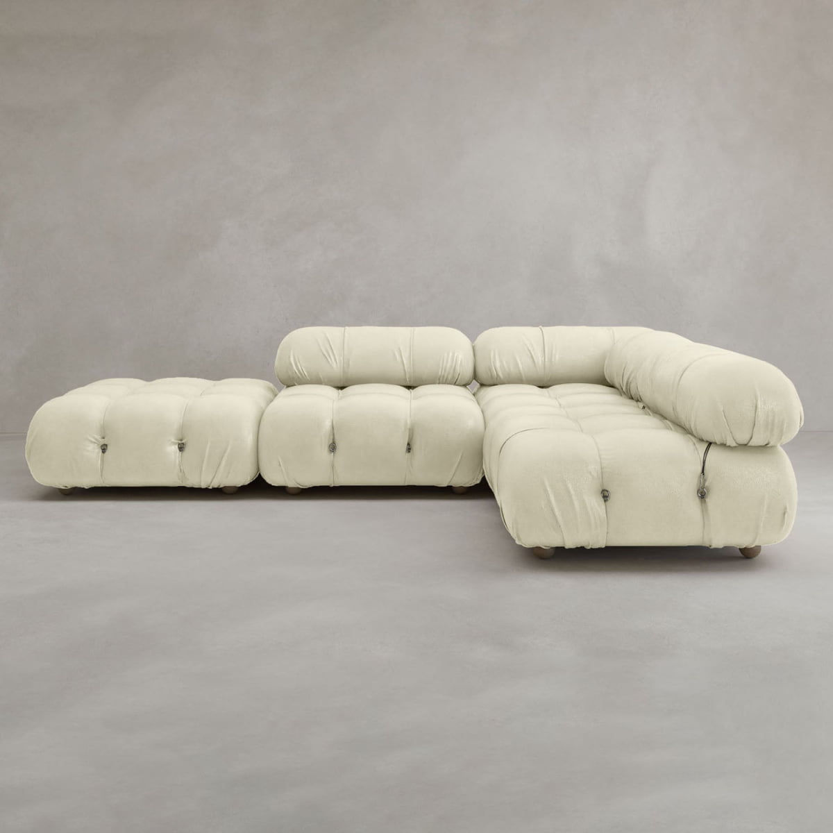 The Belmont Sofa Combination C is a modern, modular cream-colored sectional with tufted cushions and marshmallow-like curves, rounded edges, and set against a plain gray background.