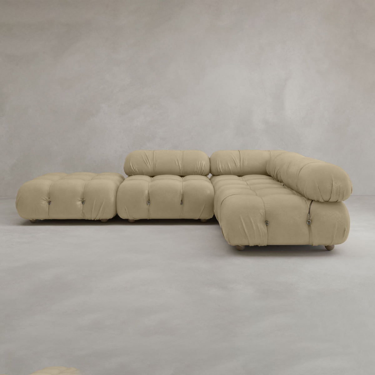 The Belmont Sofa Combination C is a modern, beige sectional with tufted details, marshmallow-like curves, rounded edges, modular design, and low seating, shown against a plain light grey background.