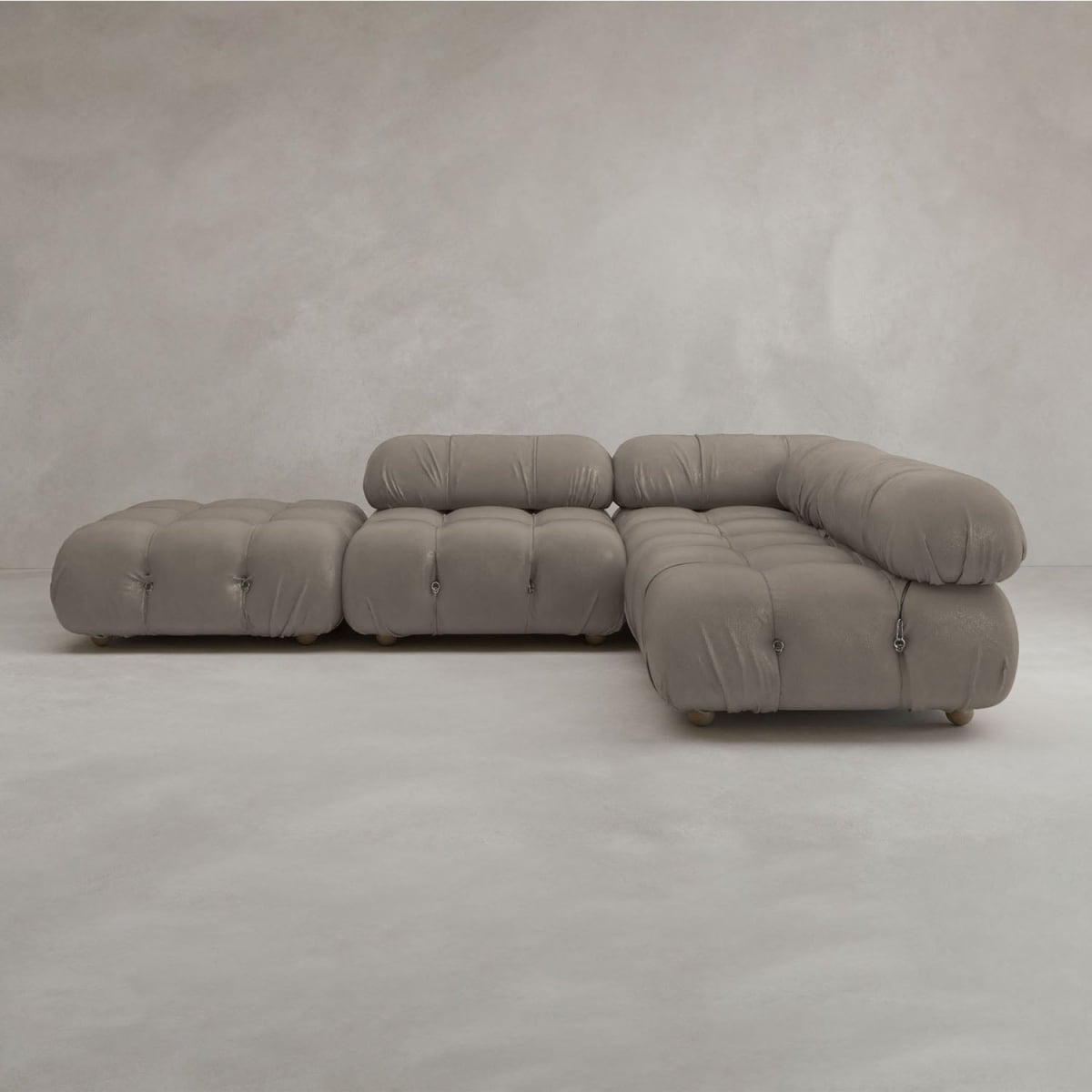 The Belmont Sofa Combination C features a modern, modular design with marshmallow-like curves, rounded tufted cushions, and low backrests, set against a neutral light grey textured wall and floor.