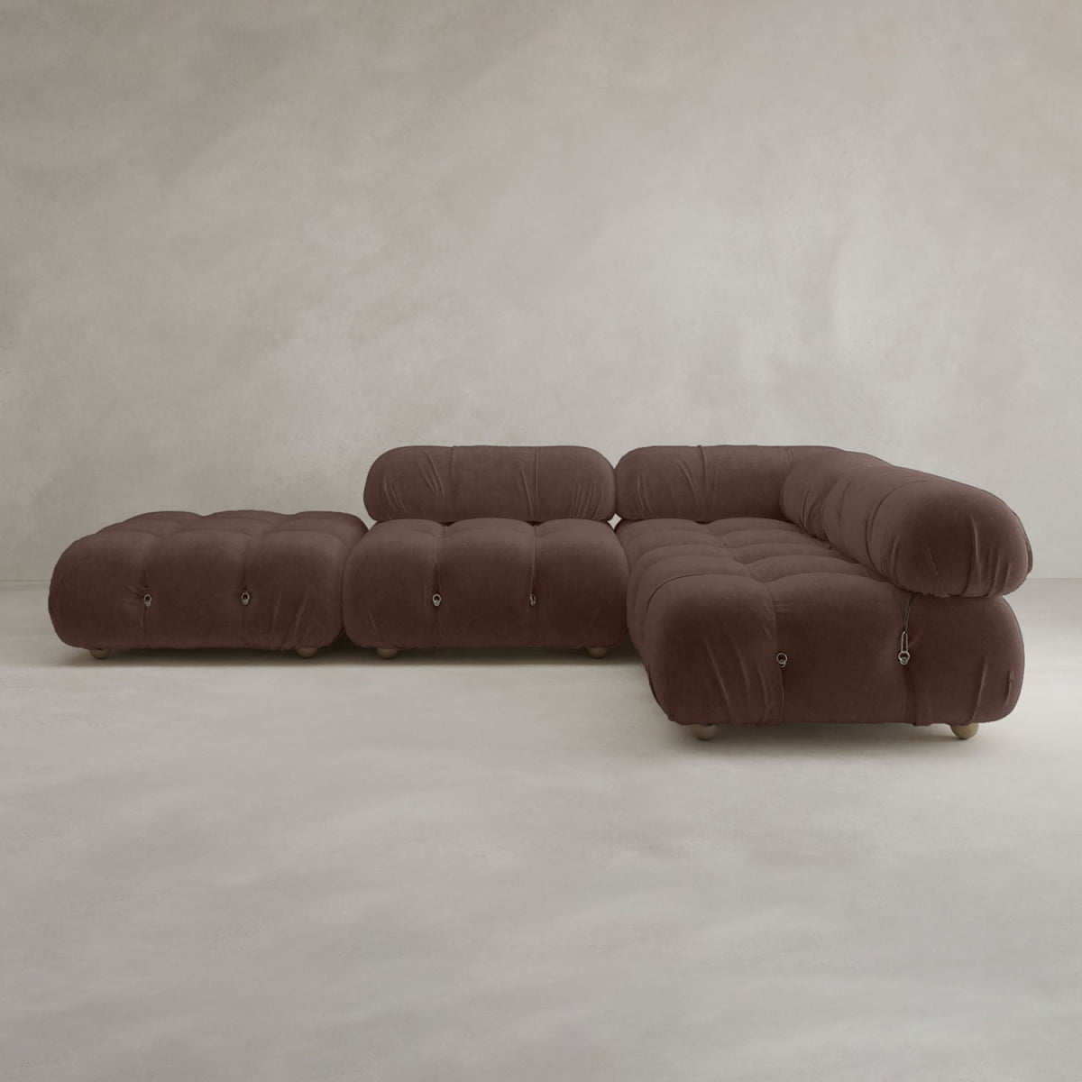 The Belmont Sofa Combination C is a modern, modular brown sectional with marshmallow-like curves, tufted cushions, and rounded edges, set against a neutral textured wall and floor.