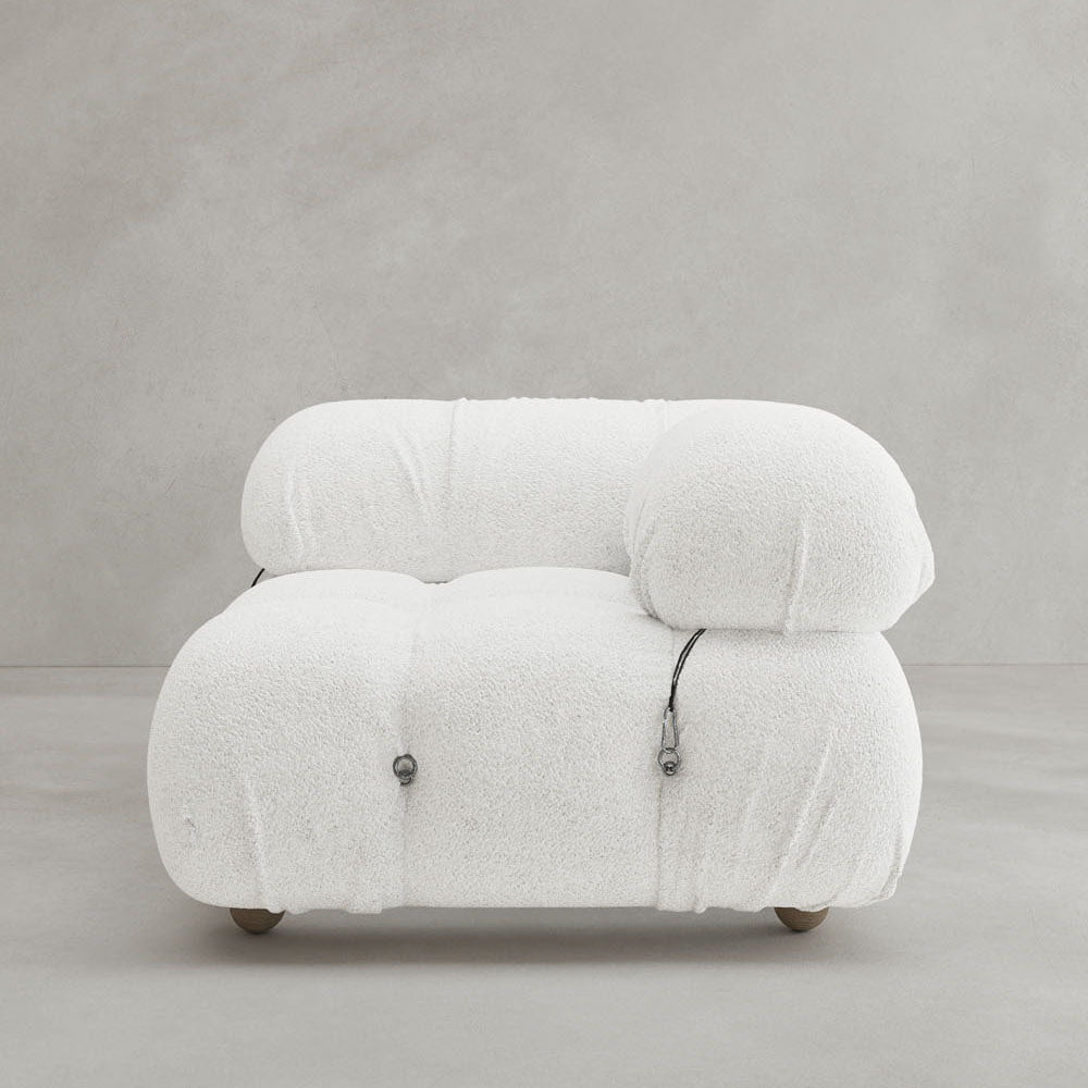 The Belmont Sofa Left Armrest features a plush, modern white design with marshmallow-like curves, tufted upholstery, minimalist metal accents, and modular elements. It is shown against a plain light gray background.