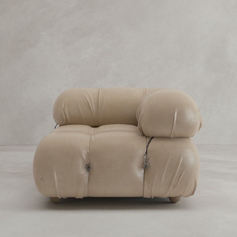 The Belmont Sofa Left Armrest features a modern, beige, plush design with rounded tufted details and visible metal fasteners, set against a light minimalist background—perfect for versatile, modular living spaces.