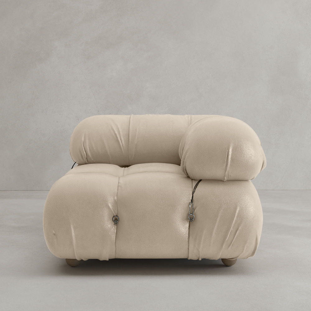 The Belmont Sofa Left Armrest features plush beige upholstery, rounded overstuffed cushions, marshmallow-like curves, and visible metal fasteners, set against a plain light gray background.