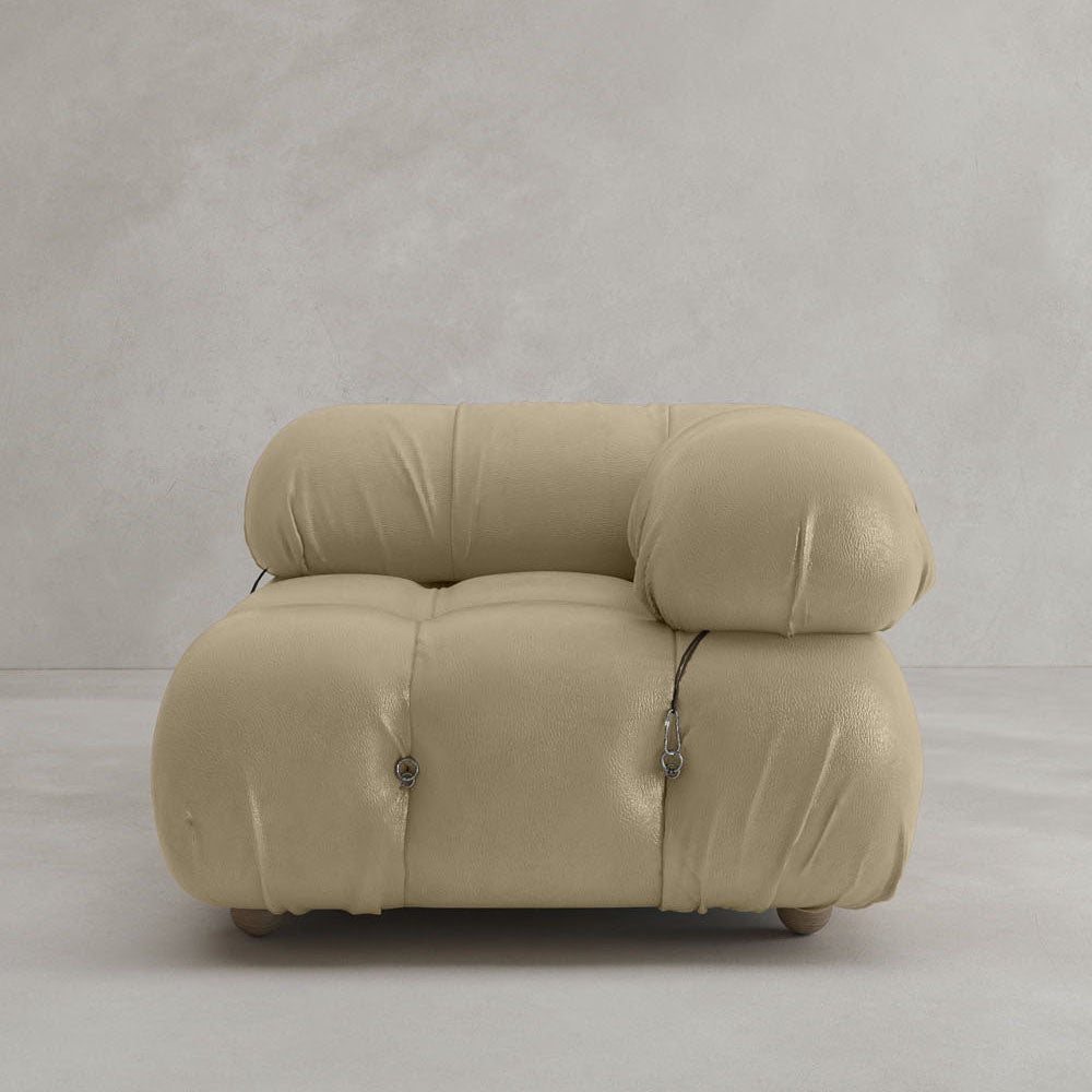 The Belmont Sofa Left Armrest features modern, plush beige upholstery with soft, rounded cushions and button detailing, set against a light gray textured wall and floor—perfect for any modular design aesthetic.