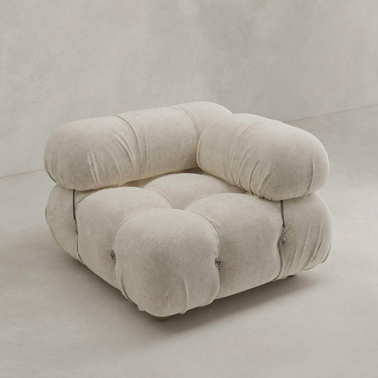 The Belmont Sofa Left Armrest features plush, overstuffed cushions in soft beige fabric with marshmallow-like curves and button accents, creating a modern look against a light, minimalist background.