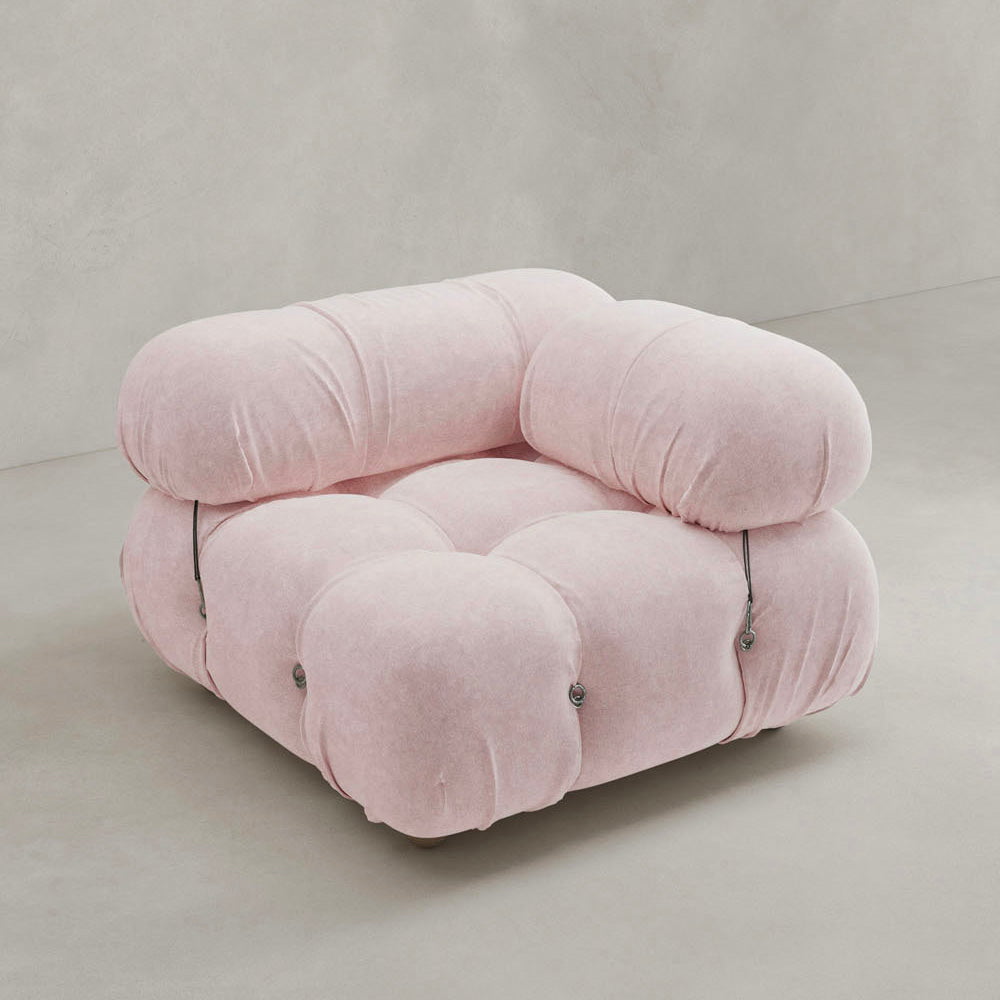 A plush, light pink Belmont Sofa Left Armrest features oversized, rounded cushions and visible tufted buttons, evoking a cloud-like feel and set against a plain, light-colored background.