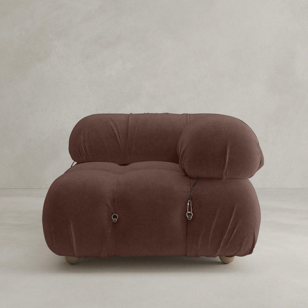 The Belmont Sofa Left Armrest is a modern, plush brown piece with a rounded, puffy design inspired by cloud-like sofas. It features soft upholstery, metal clip accents, and is set against a plain light gray background.
