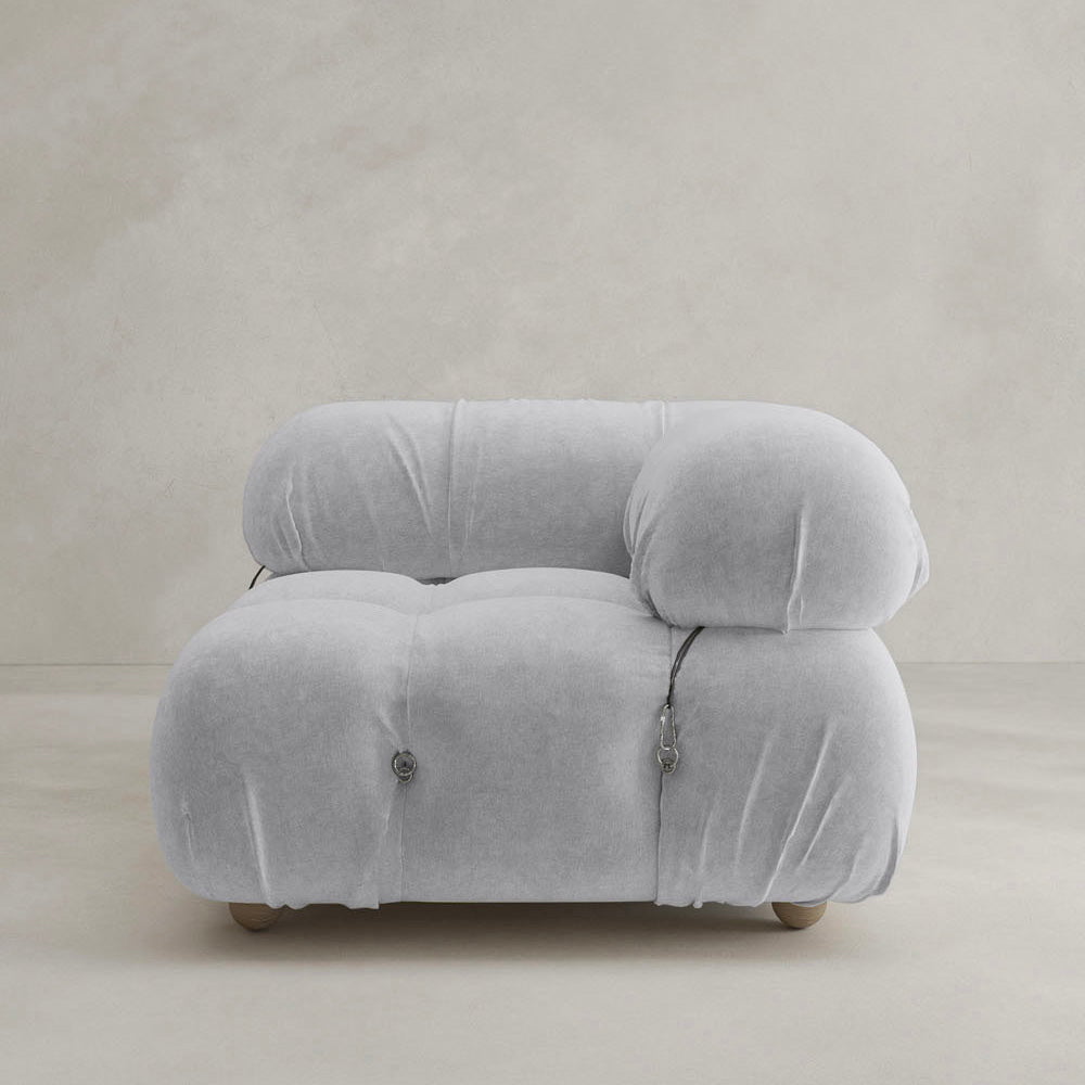 The Belmont Sofa Left Armrest features a modern, plush design in light gray with marshmallow-like curves, rounded and overstuffed for comfort, visible seams, and set against a plain beige background.