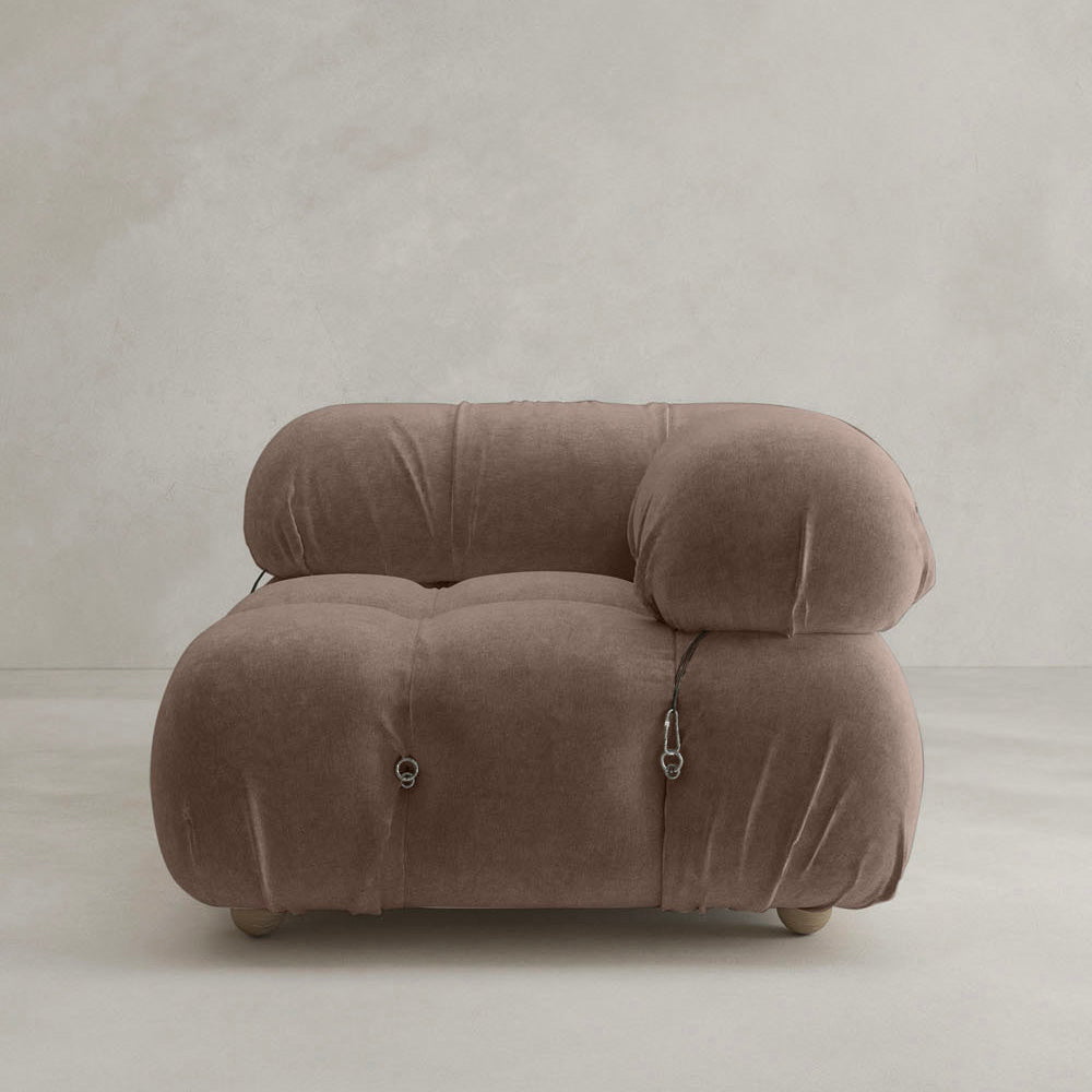 The Belmont Sofa Left Armrest features plush, brown upholstery with distinctive marshmallow-like curves and rounded, oversized cushions, set against a plain light gray wall and floor for a modern look.