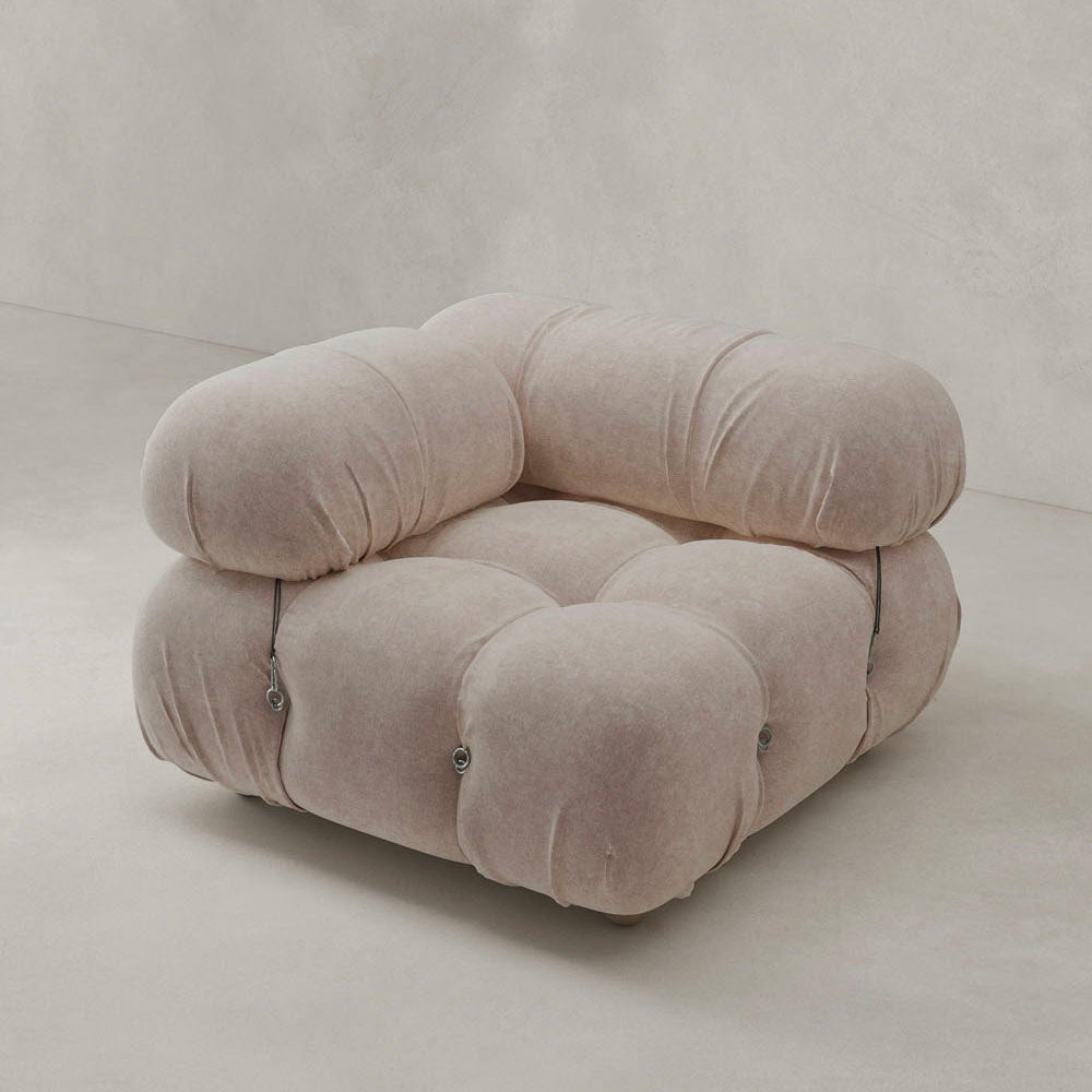 The Belmont Sofa Right Armrest, a plush light beige piece with tufted, rounded cushions and a modern low-profile modular design, sits on a smooth, light-colored floor against a plain wall.