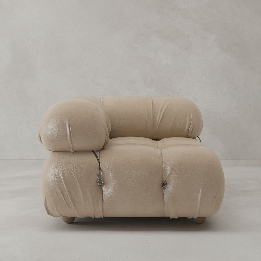 The Belmont Sofa Right Armrest features plush, rounded cushions upholstered in beige leather with visible metal fasteners, presenting a modern classic look against a plain light gray background.