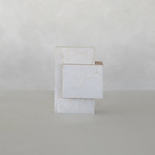 The Bianca Tall is a minimalist white onyx sculpture with visible veins, featuring two rectangular plinths interlocked at a right angle against a neutral, textured background.