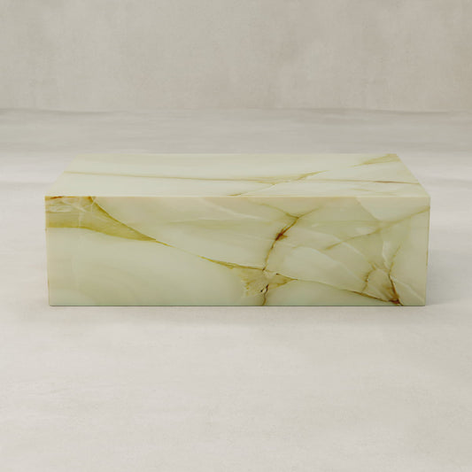 The Blanchaire Onyx Coffee Table, crafted from glossy light onyx with tan and gold veining, features a luminous finish. Placed on a smooth surface with a neutral background, it brings refined elegance to any space.