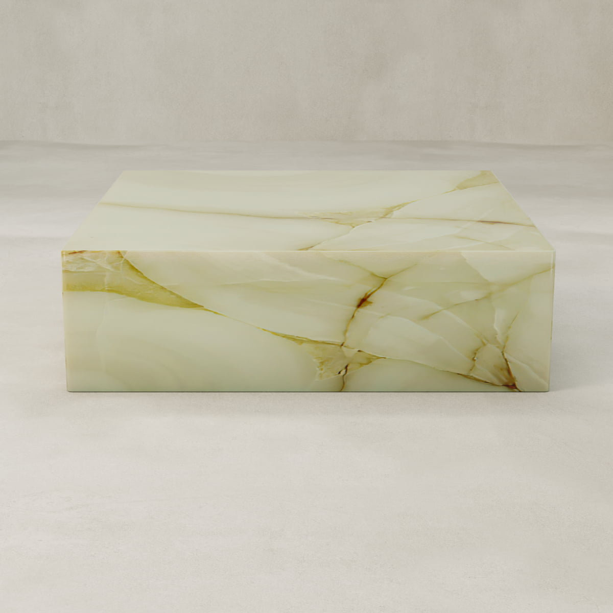 The Blanchaire Onyx Coffee Table XL, rectangular and light beige with natural veining and a luminous finish, rests on a smooth pale floor against a matching neutral background.