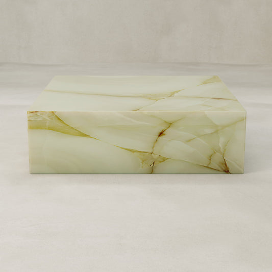 The Blanchaire Onyx Coffee Table XL, rectangular and light beige with natural veining and a luminous finish, rests on a smooth pale floor against a matching neutral background.