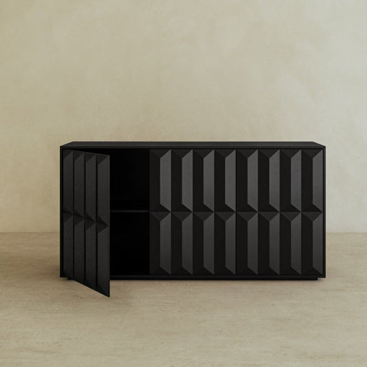 A modern black Braemar Console Large with geometric patterns stands against a light beige wall and floor. One cabinet door is open, revealing empty shelves—showcasing avant-garde design flair.