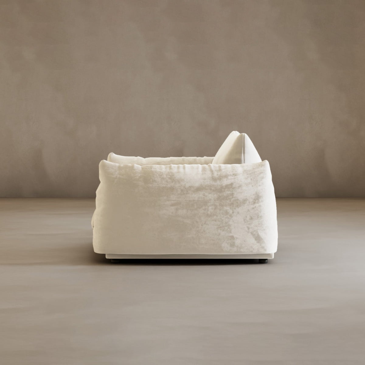 The Calypso Arm Chair combines modern elegance and plush comfort with its textured white fabric, shown from the side on a neutral floor against a minimalist beige wall.