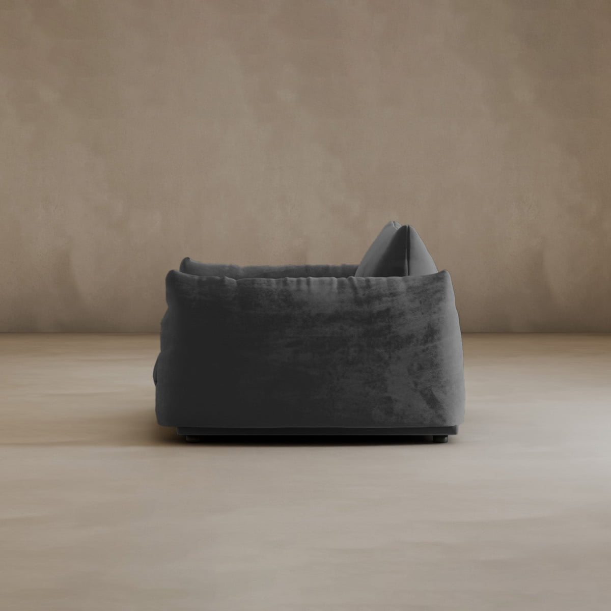 The Calypso Arm Chair, in modern deep gray with a plush soft cushion, is viewed from the side on a light beige floor against a matching neutral wall.
