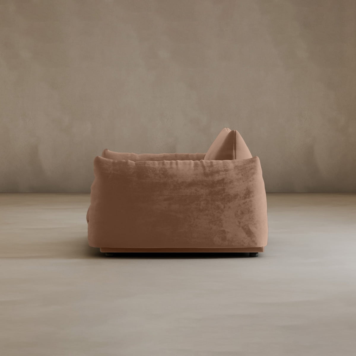 The Calypso Arm Chair, a plush light brown seat with a large back cushion, is shown in side view against a plain beige wall and smooth floor, highlighting its modern elegance.