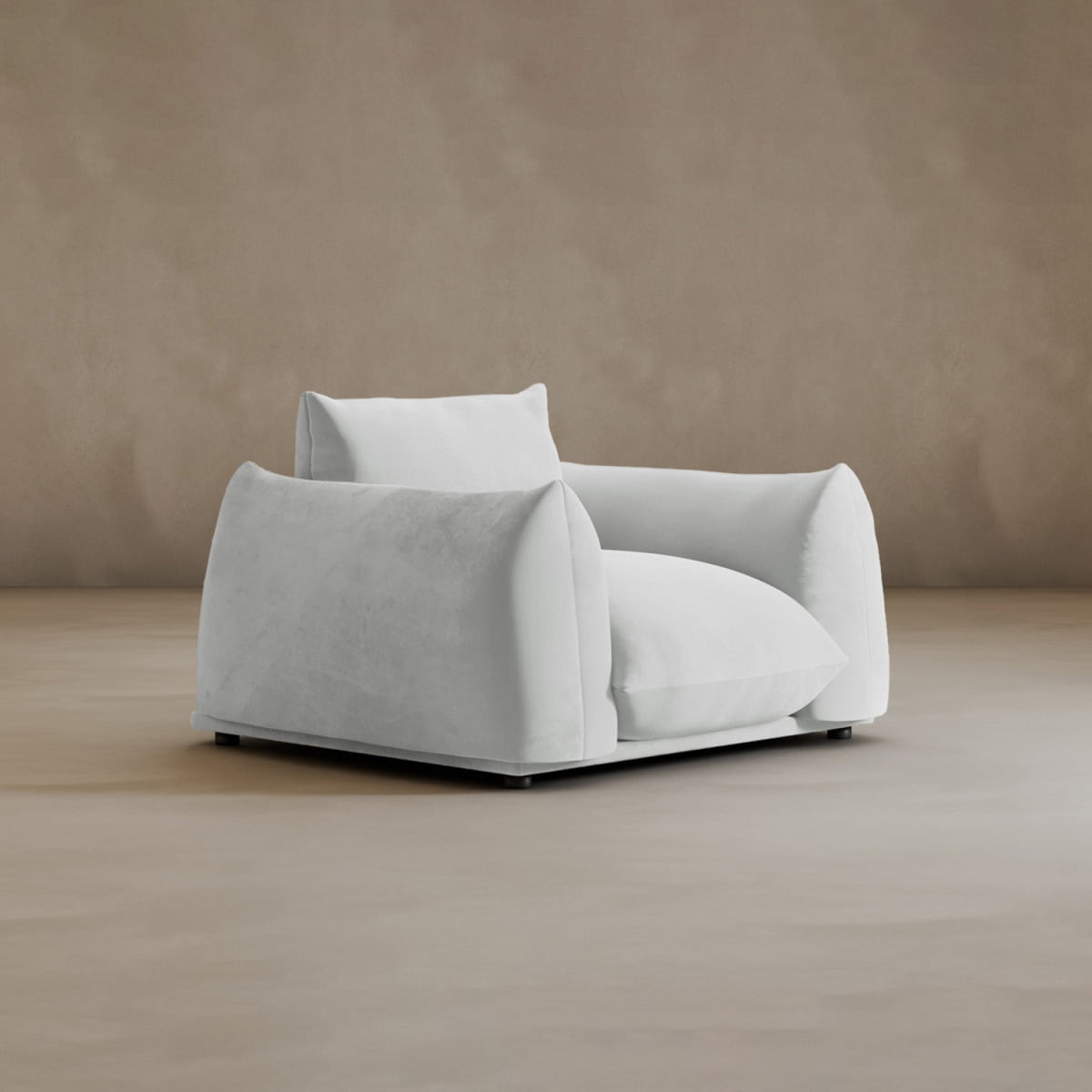 The Calypso Arm Chair is a modern, oversized white armchair with wide armrests and soft cushions, providing plush comfort. It stands on a light brown floor against a beige wall, showcasing modern elegance.