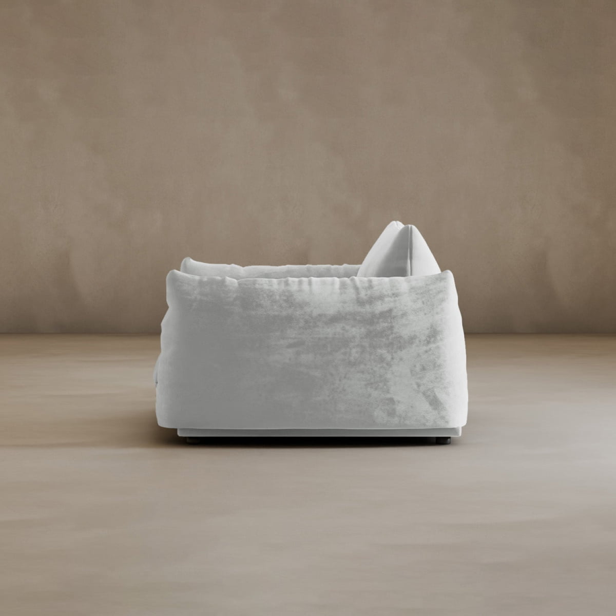 The Calypso Arm Chair showcases modern elegance with a plush white silhouette and velvety fabric cover. Its relaxed, cushioned design and single back pillow offer plush comfort, shown side view against a plain beige background.