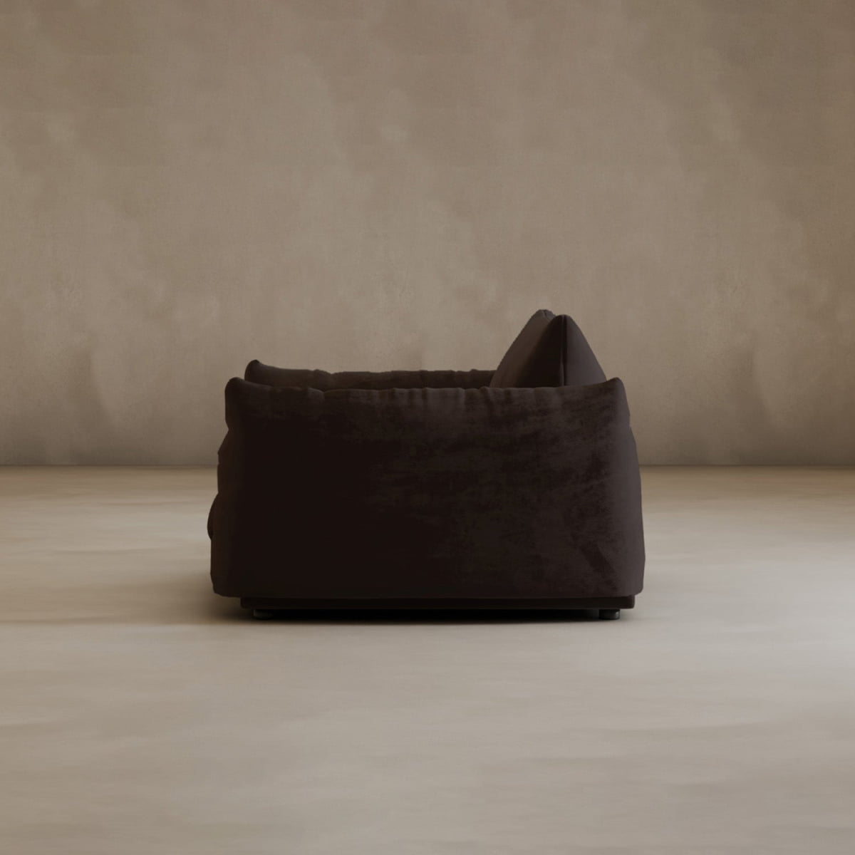 The Calypso Arm Chair, upholstered in plush dark brown fabric with a textured surface, is displayed side-on against a plain light beige wall and floor, giving the scene a modern and minimal look.