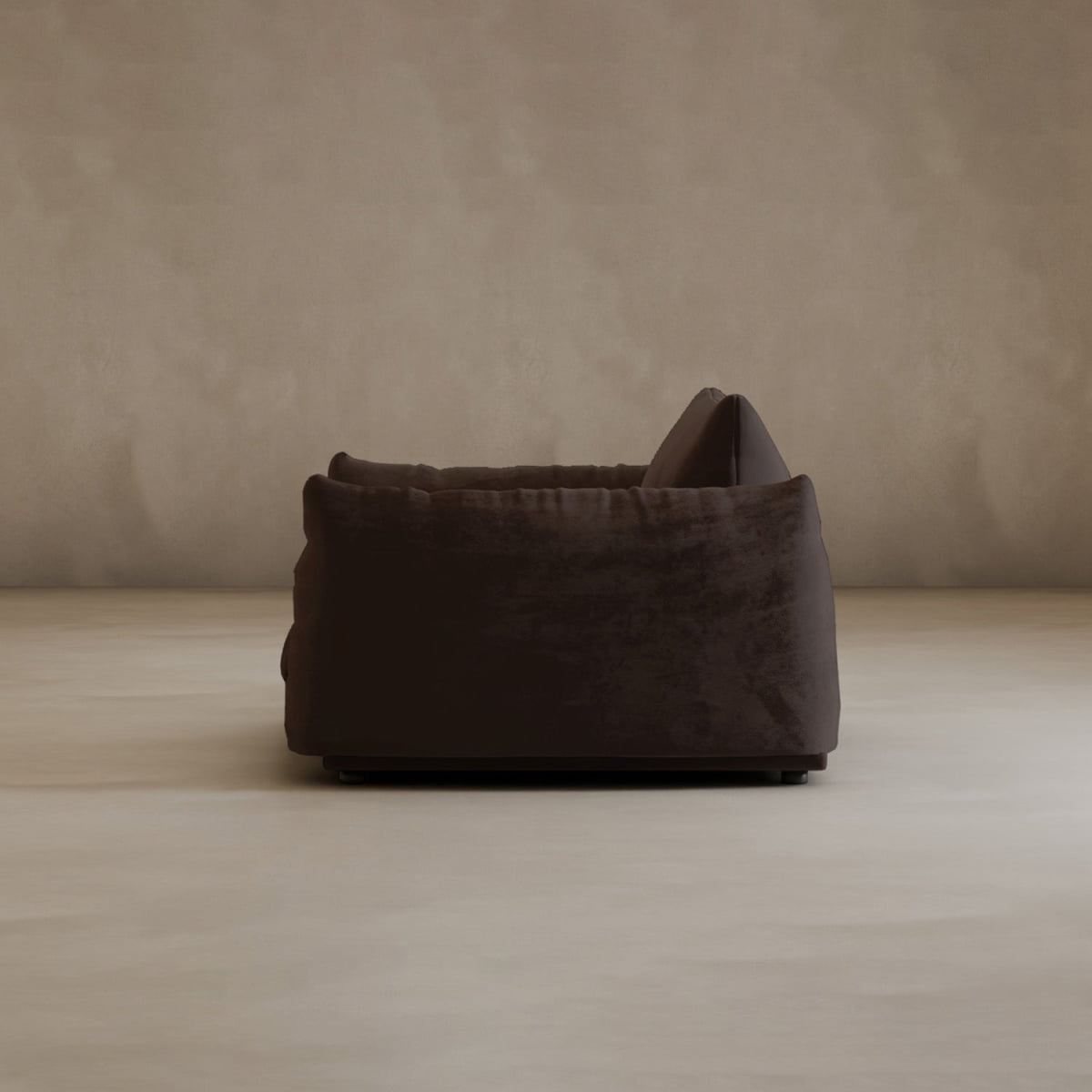 The Calypso Arm Chair is shown in dark brown from the side, set against a plain light beige wall and floor. It features modern elegance and plush comfort, with a single cushion adding to its soft, inviting look.