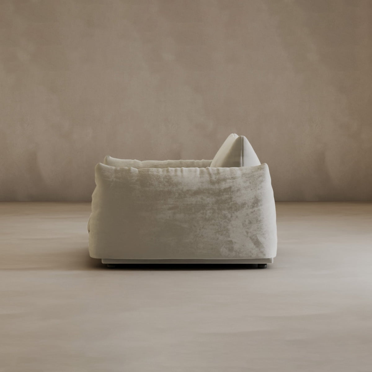 The Calypso Arm Chair, in plush light beige with soft rounded edges and a fluffy cushion on top, sits at the center of a minimal, neutral-toned room, radiating modern elegance and comfort when viewed from the side.
