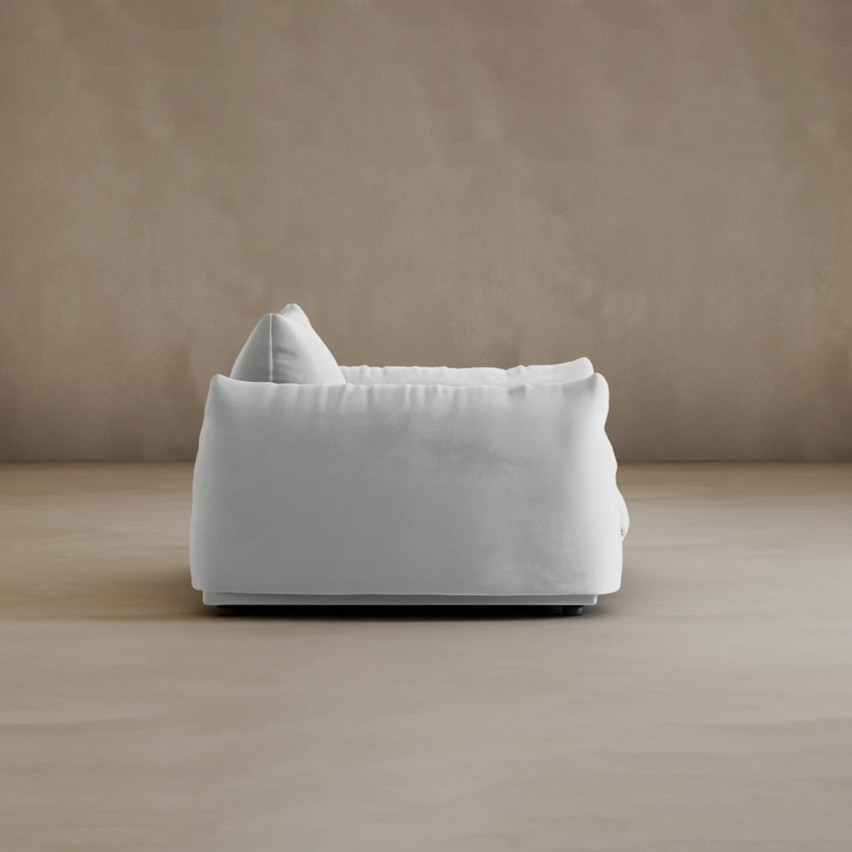 The Calypso Arm Chair, shown in modern white upholstery, exudes plush comfort and elegance in a minimalistic room with a light beige floor and matching beige wall backdrop.