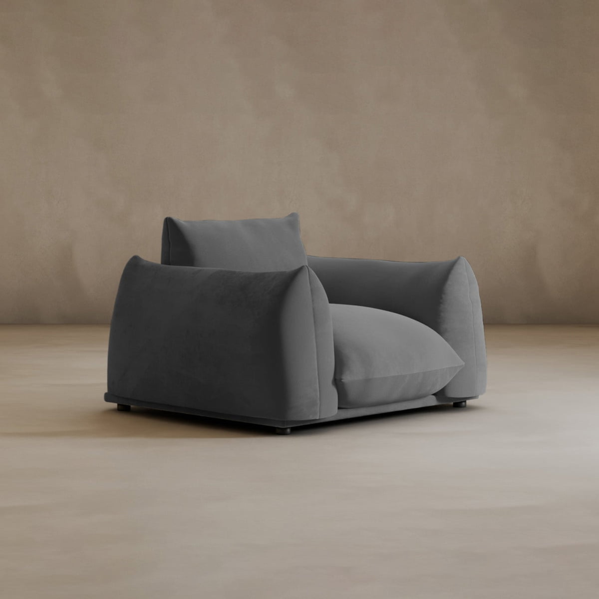 The Calypso Arm Chair features soft, dark gray upholstery, plush cushions, and wide armrests. Its oversized modern design sits on a light-brown floor against a matching background, offering both elegance and comfort.