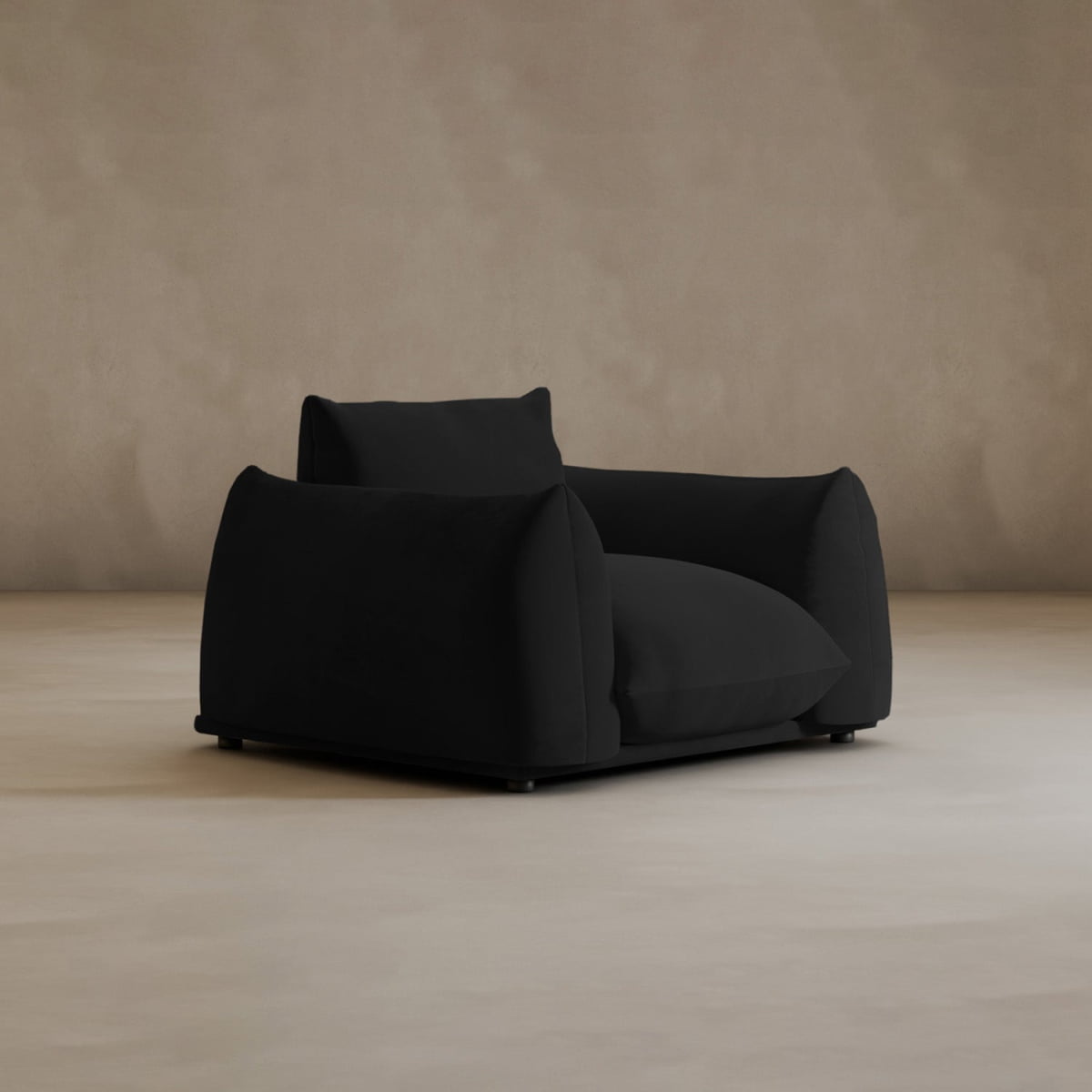 The Calypso Arm Chair, with its oversized design, plush cushions, and wide armrests, brings modern elegance to any space as it rests on a smooth beige floor against a light brown wall.