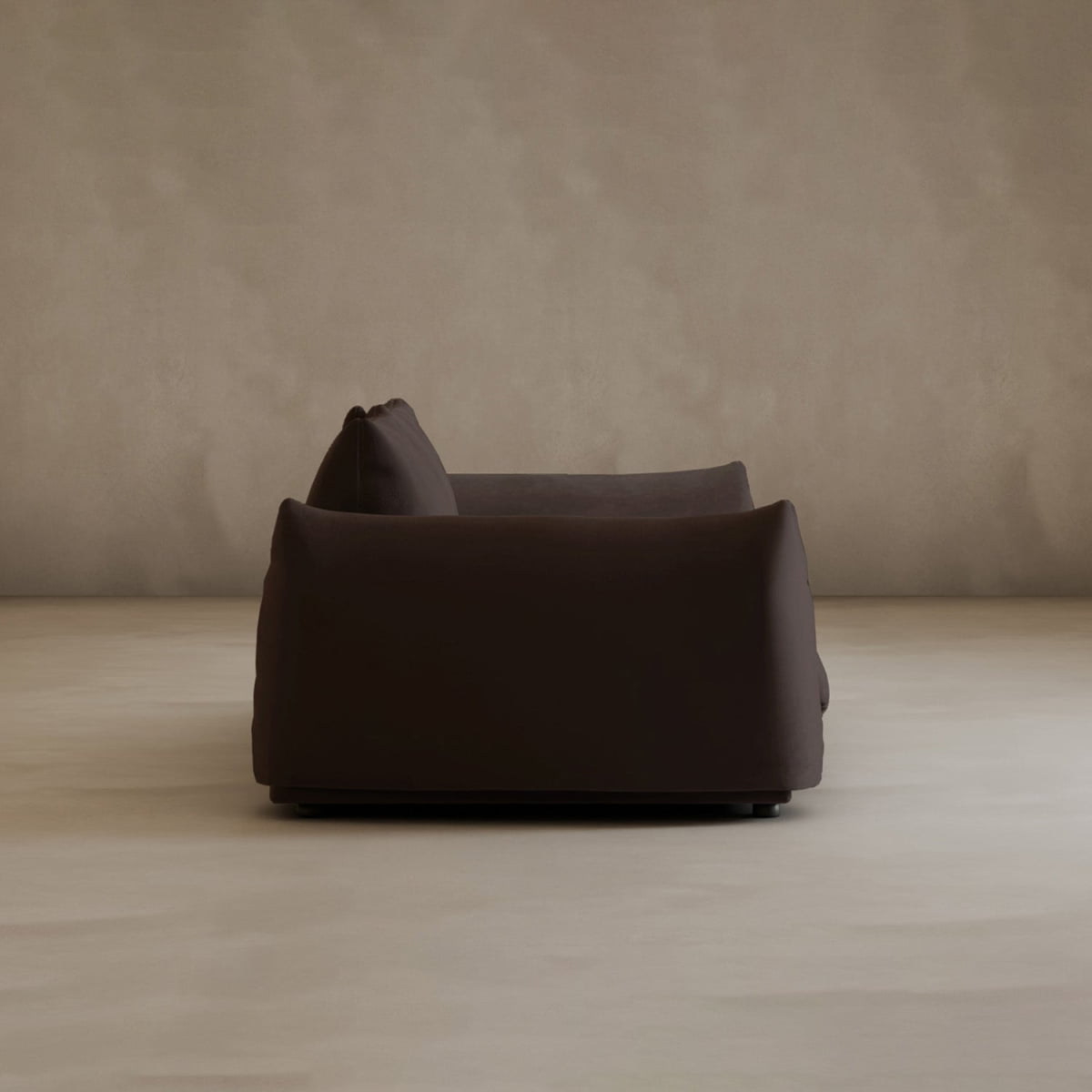 A dark brown Calypso Loveseat, featuring modern elegance, is seen from the side as a plush 2-seater in an empty room with beige walls and a light-colored floor.