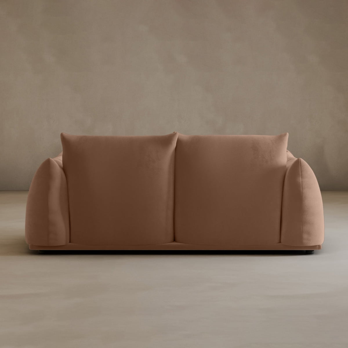 The Calypso Loveseat features a modern, minimalist design with rounded, plush arms and no visible legs, adding elegance to any space. Its shown here against a plain beige wall and floor.